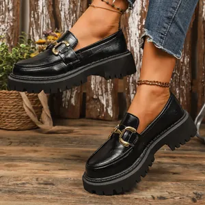 Side view detail of black chunky platform loafers featuring a decorative gold buckle