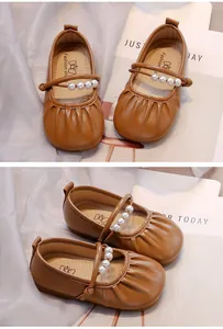 Detalle de zapatos Mary Jane marrones para niña con perlas y pliegues.