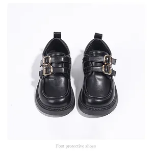 Detailed top-down view of black girls' loafers featuring double gold buckles and thick soles.