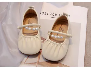 Primer plano de los zapatos Mary Jane crema para niña con una correa de perlas