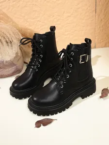 Close-up of black British style Martin boots with thick platform soles and buckle detail.