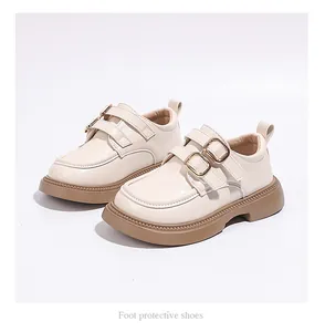 Detail view of girls' cream Mary Jane shoes with gold buckles and chunky brown soles.
