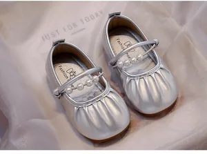 Vista detallada de zapatos de princesa plateados con correa de perlas y diseño plisado