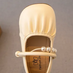 Primer plano de bailarinas de piel color crema para niña con elegante correa de perlas