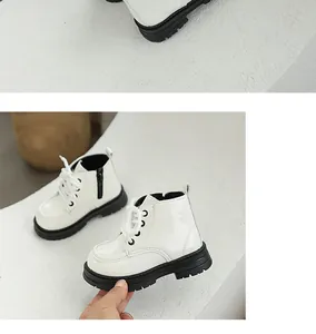Close-up detail of white patent leather children's Martin boots with side zipper and black sole