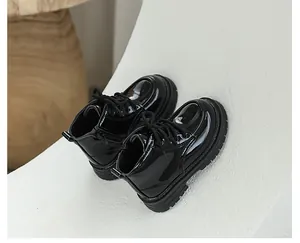 Detailed view of shiny black patent leather kids Martin boots with side zip and laces