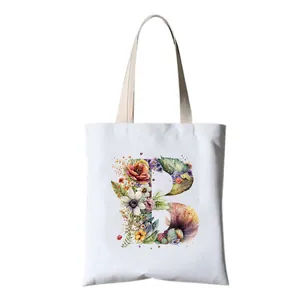 Detailed view of a beautiful watercolor floral letter B print on white canvas tote bag