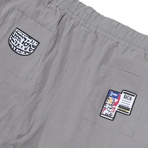 Primer plano del pantalón casual de lino gris con parches gráficos en los bolsillos traseros.