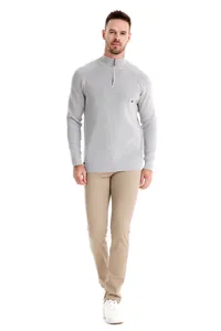 Full body studio shot of a man wearing a grey half-zip knit sweater and tan pants