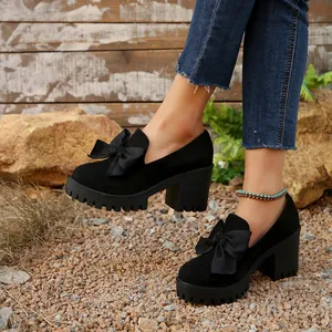 Close-up detail of stylish black platform chunky high heels with elegant bow decoration