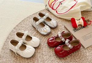 Détail de chaussures de princesse pour filles avec perles et bouts plissés en trois couleurs.