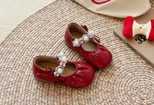 Détail des chaussures de princesse rouges pour filles avec plis et décoration de perles
