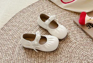 Vue détaillée des Mary Janes crème pour filles avec bride perlée et nœud élégant