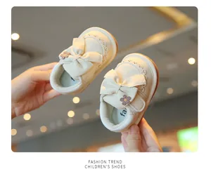 Scarpe da passeggio beige per neonati con elegante fiocco mostrate in un primo piano a mano