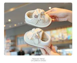 Primo piano di scarpe color crema per bambini con fiocchi decorativi e piccoli fiori