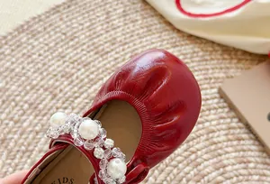 Gros plan détaillé de chaussures princesse plissées rouges pour filles avec perles