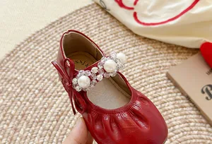 Vue détaillée de chaussures de princesse rouges pour filles avec perles et cuir plissé.