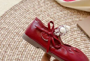 Gros plan de chaussures de princesse rouges pour filles avec perles et nœud élégant
