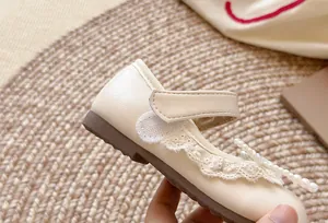 Détail latéral de chaussure princesse beige avec dentelle et nœud en perles