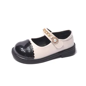 Elegante cremeweiße und schwarze Mädchen Mary Janes mit Goldkette und Perlenblumen-Akzent