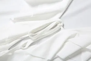 Vue détaillée du lien à la taille et des volants sur une élégante robe blanche.