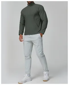 Vue complète d'un homme portant une veste de sport verte et un pantalon gris clair.