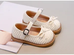 Dettaglio di scarpe Mary Jane intrecciate color crema per bambina con fiocco e fibbia