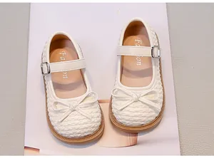 Vista dall'alto di scarpe basse bianche da bambina con fiocco e trama intrecciata