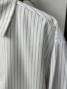 Close-up of white long-sleeve shirt featuring thin black vertical stripes and fabric texture