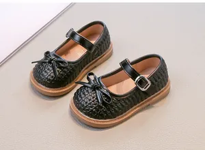 Dettaglio di eleganti ballerine nere intrecciate per bambina con fiocco e fibbia.