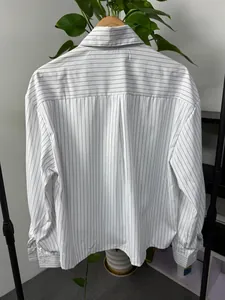 Detail view of men's loose long-sleeved shirt with black vertical stripes