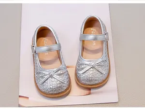 Vista dall'alto di ballerine argento per bambina con fiocchi decorativi e trama intrecciata.