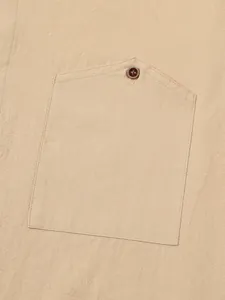 Close-up detail of a men's linen shirt pocket with button and textured fabric