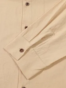 Macro detail of men's beige linen shirt cuff showing natural fabric texture and brown buttons