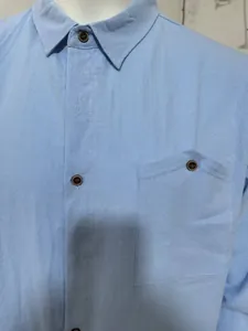 Close-up of light blue linen shirt showing fabric texture and pocket detail