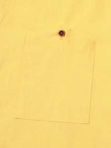Close-up detail showing the chest pocket and button on a yellow linen casual shirt for men.