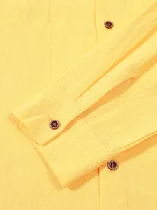 Macro view of yellow linen-textured fabric and brown button detail on men's shirt