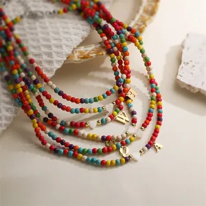 Close-up of colorful turquoise seed bead necklaces with heart and gold initial charms