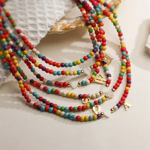 Detailed view of colorful seed bead necklaces with gold initial and heart charms.