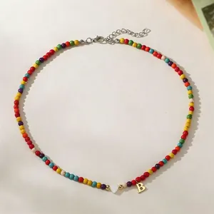 Colorful turquoise bead choker with white heart and gold letter B pendant detail