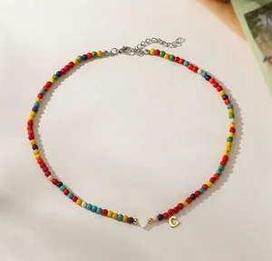 Close-up detail of colorful turquoise bead necklace with white heart and golden letter C pendants