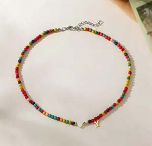 Close-up detail of a colorful boho beaded necklace featuring a white heart bead and letter Y.