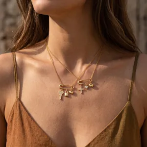 Detalle de collares de imperdible dorados en capas con dijes variados en modelo
