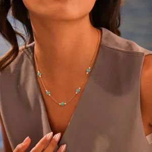 Detalle de un collar de acero dorado con turquesas redondas y piedras de circón