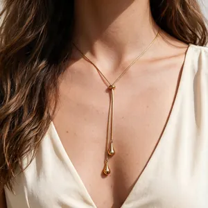 Détail d'un collier en Y minimaliste en acier inoxydable doré avec des pendentifs gouttes