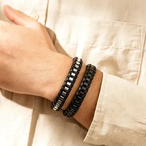 Nahaufnahme von geflochtenen Herrenarmbändern aus Leder und Edelstahl am Handgelenk.
