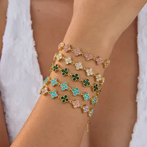 Detailansicht von goldenen Edelstahlarmbändern mit bunten Strass-Blumenanhängern