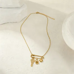 Detalle de un collar con colgante de imperdible dorado con dijes de corazón, llave y candado