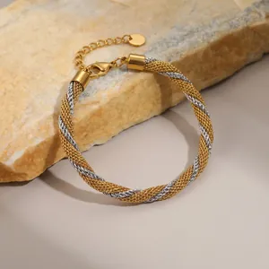 Detailansicht eines gold-silbernen Mesh-Armbands auf einem Natursteinuntergrund.