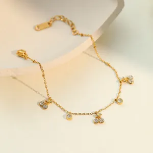 Détail d'un bracelet en acier doré avec des breloques cerise serties de cristaux.